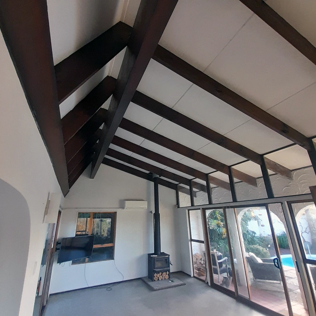 unpainted brown beams with a fireplace and a pool outside