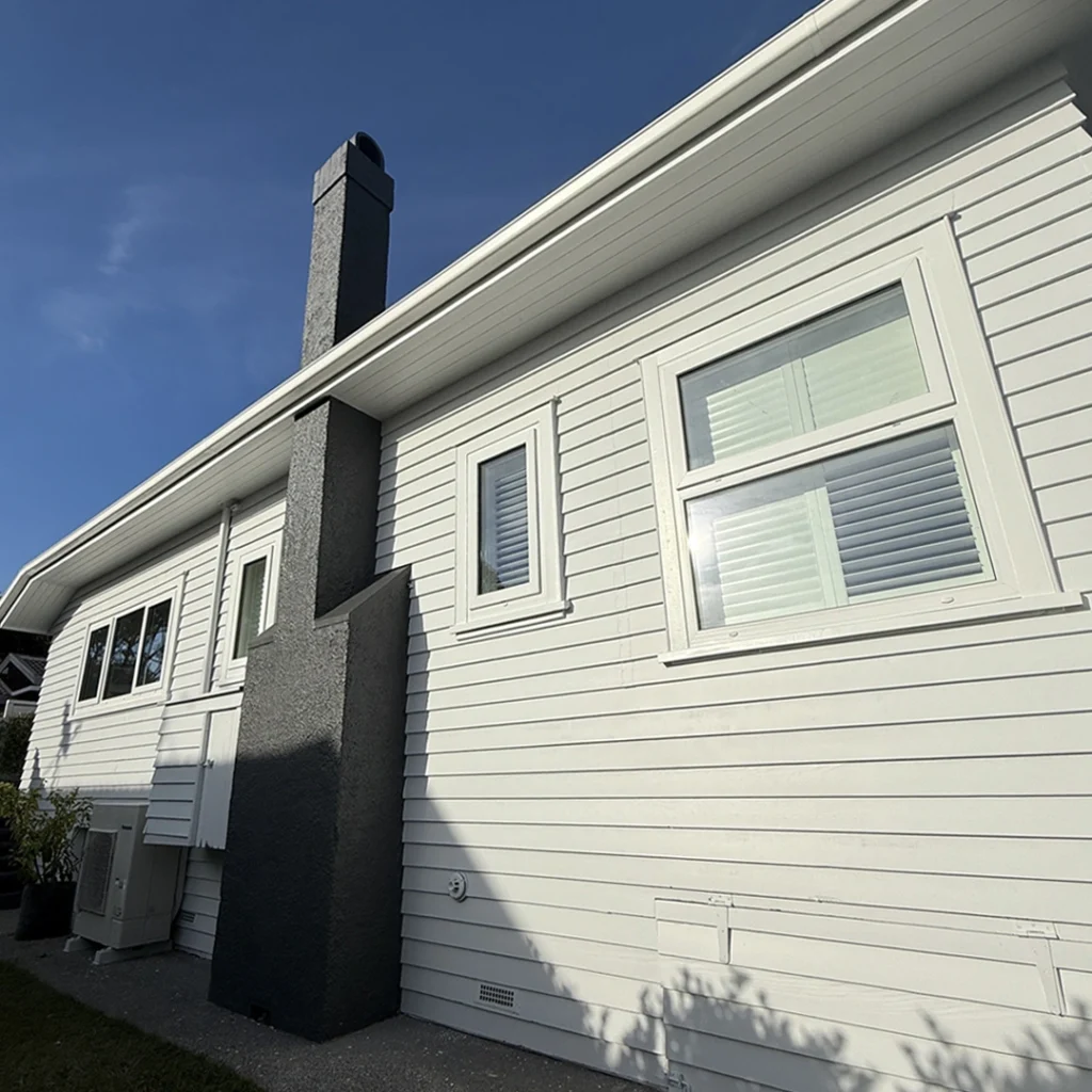 The image shows a well-kept house façade in Bayswater, Auckland. The fresh layer of paint emphasises the home's architectural characteristics, giving it a clean, modern, and stylish appearance. The walls are painted in a smooth, neutral tone that is nicely offset by crisp white trim and window frames, which provide contrast and elegance. The doorway is inviting and complements the renovated exterior. The beautiful finish demonstrates excellent craftsmanship, considerably boosting the home's street appeal while remaining well-kept and fashionable.